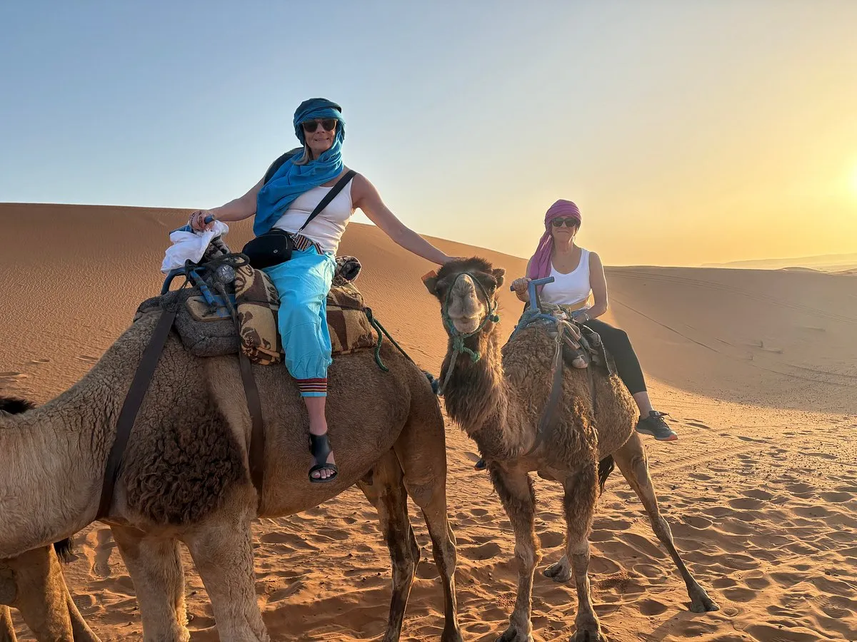 Morocco Happiness Tours guests riding camels in the Sahara desert